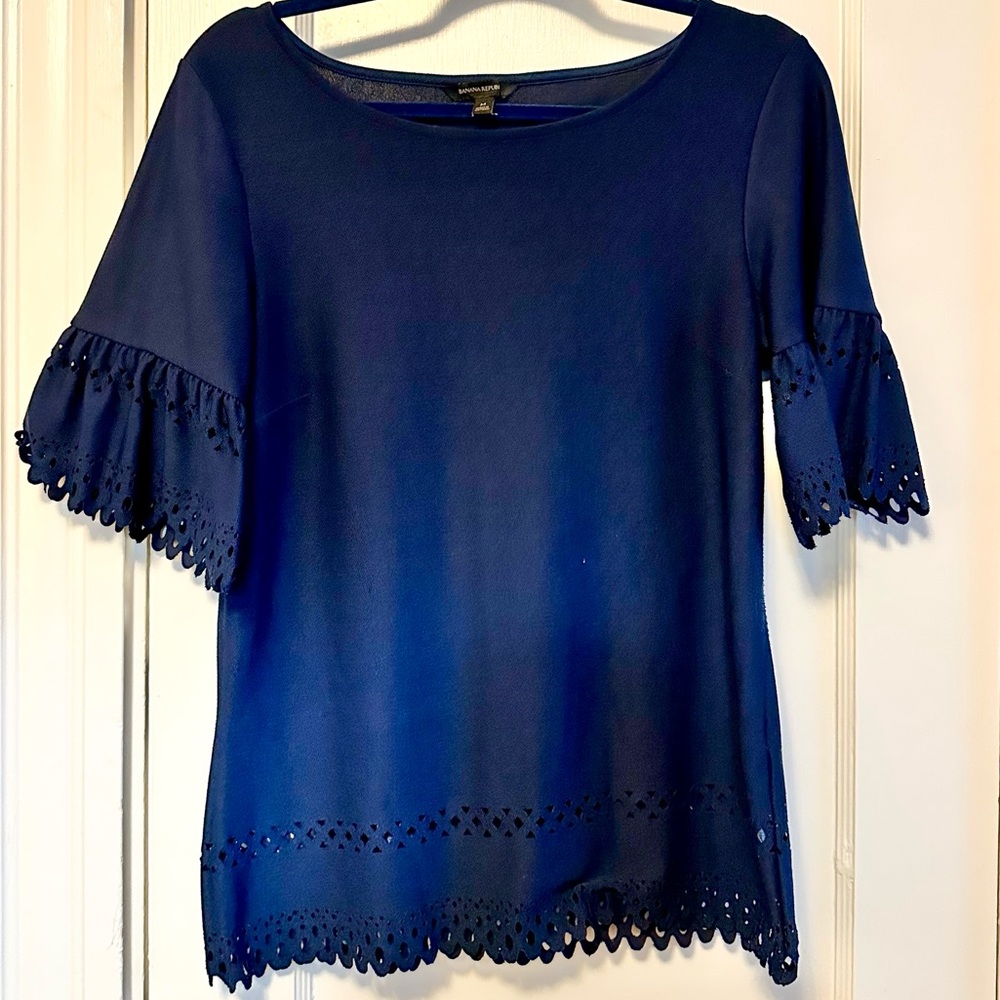 Navy blouse with cutout lace-like detailing on sleeves and hem